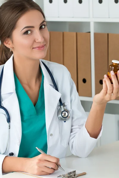 微笑的女性医学医生抱着药丸瓶 图库图片