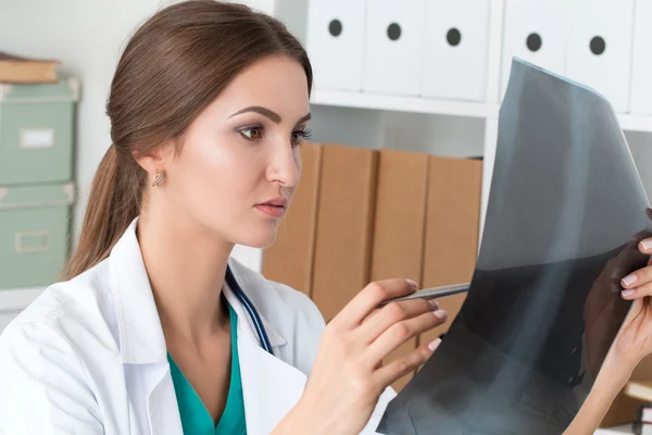 Young female doctor looking at lungs x-ray image — Stock Photo, Image