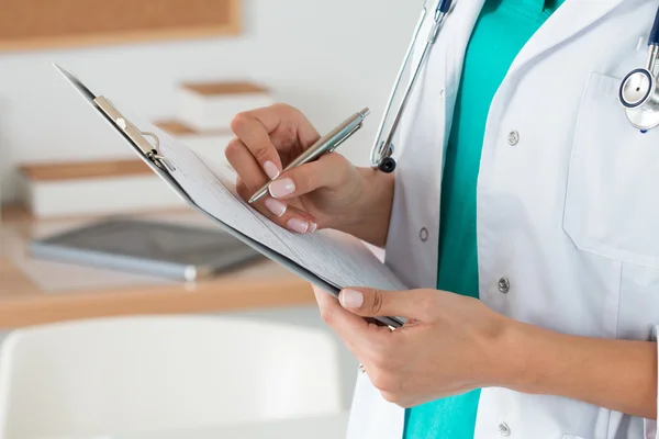 Vista de cerca de las manos del médico femenino llenando el registro del paciente — Foto de Stock