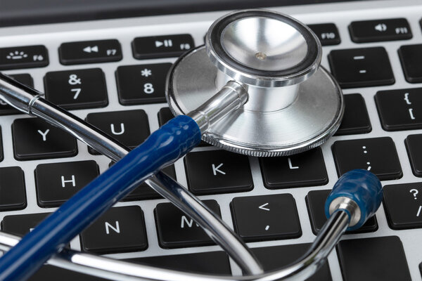 Stethoscope lying on laptop keyboard closeup