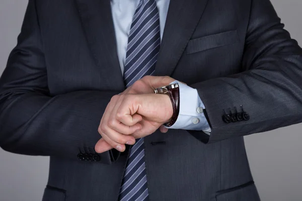 Молодой бизнесмен смотрит на свои наручные часы, проверяя время — стоковое фото