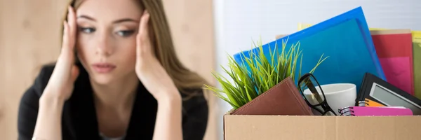 Young dismissed female worker sitting near the carton box with h — Stock Photo, Image