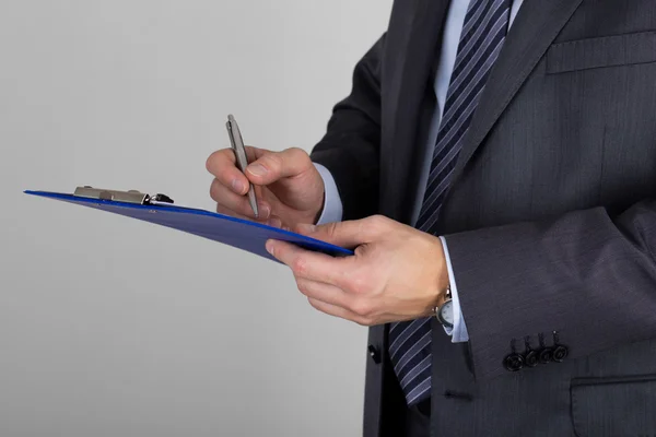 Business man holding clipboard and signing documents — Stock fotografie