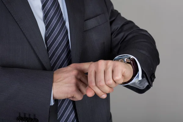 Business man looks at his wrist watch checking the time — 图库照片