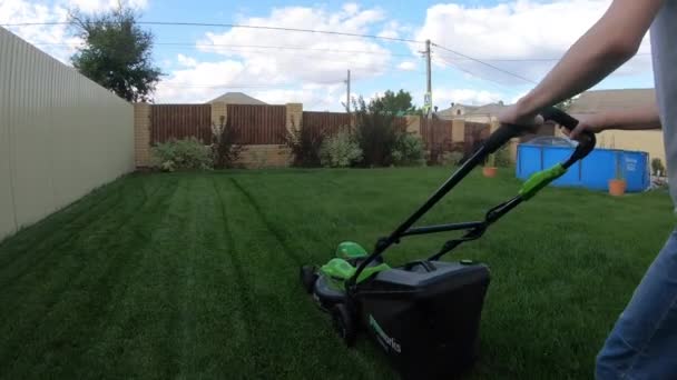 A teenager mows the lawn with a lawn mower. — Stock Video