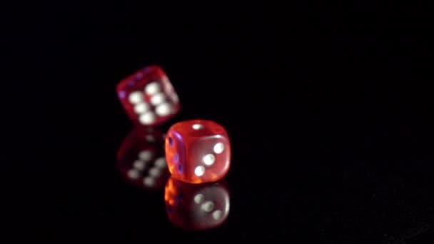 Movimento lento di cubi di gioco rotolamento sul tavolo nero. dadi del casinò rosso rotolamento — Video Stock