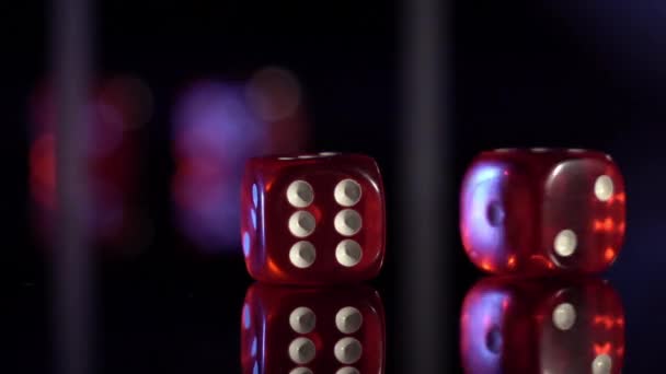 Movimento lento di cubi di gioco rotolamento sul tavolo nero. dadi del casinò rosso rotolamento — Video Stock