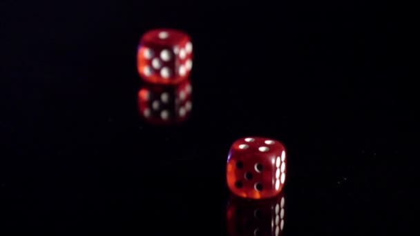 Movimento lento di cubi di gioco rotolamento sul tavolo nero. dadi del casinò rosso rotolamento — Video Stock