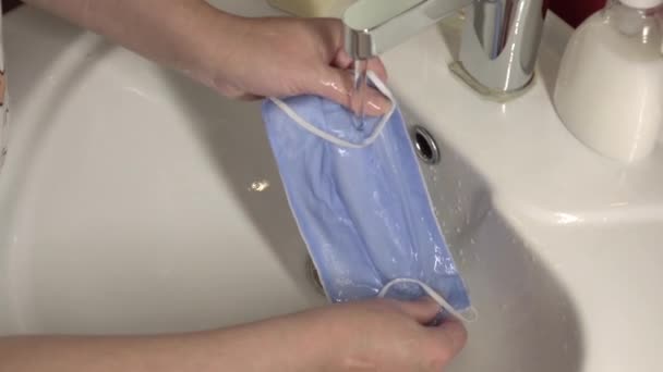 Lavare una maschera medica nel lavandino. Maschera medica riutilizzabile in cotone per la protezione da Covid-19. — Video Stock