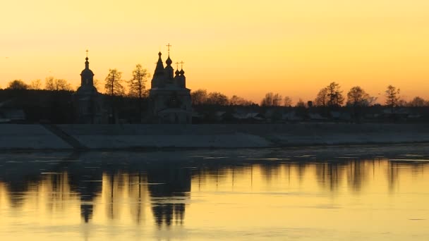 Ortodoxa kyrkan på flodbanken. Flodens istäckta strand under senhösten. — Stockvideo