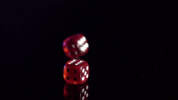 Movimento lento di cubi di gioco rotolamento sul tavolo nero. dadi del casinò rosso rotolamento — Video Stock