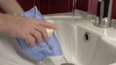 Lavaboda tıbbi maske yıkıyorum. Cotton, Covid-19 'dan korunmak için yeniden kullanılabilir tıbbi maske..