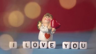 Sevimli melek ve gül yapraklarının arka planında aşk sözleri. Sevgililer Günü. Tatiller için kartpostal.