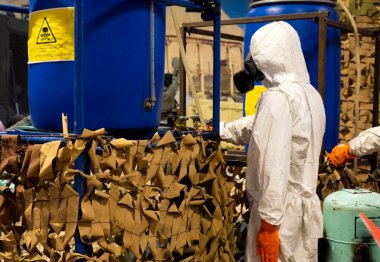 Laboratuvarda kimyasal ve biyolojik silah üretimi için koruyucu giysiler giyen insanlar..