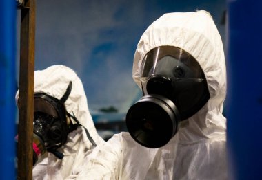 Laboratuvarda kimyasal ve biyolojik silah üretimi için koruyucu giysiler giyen insanlar..