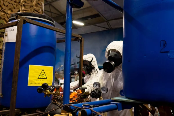 화학 무기와 생물학 무기의 생산을 위해 실험실에서 보호용 양복을 입고 있는 사람들. 스톡 사진