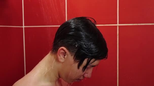 A young man in the shower. A teenager washes under a stream of warm water in the bathroom. — Stock Video