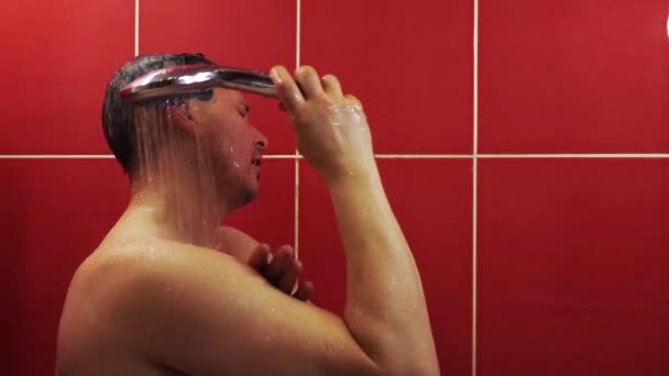 Ein Mann unter der Dusche. Ein Mann mittleren Alters wäscht sich im Badezimmer unter einem Strom aus warmem Wasser. — Stockvideo