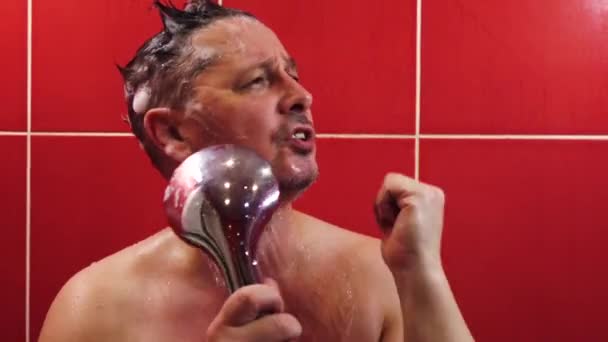 En lycklig man sjunger med en dusch som en mikrofon medan han tvättar sig i badkaret — Stockvideo