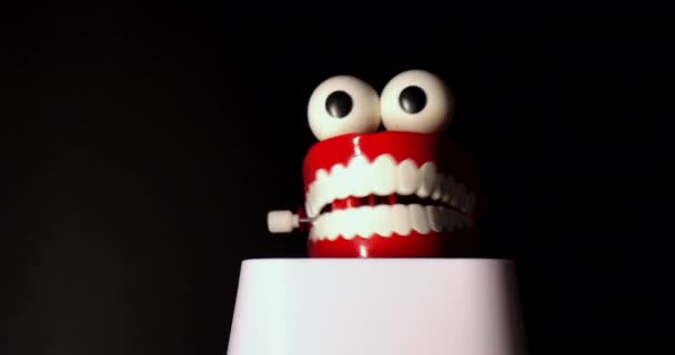 白い歯と黒い背景に隔離された大きな目を持つ笑顔のおもちゃのプロテーゼ。. — ストック動画