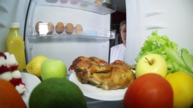 Adam yiyecek için buzdolabına bakıyor. Tütsülenmiş tavuk mu yoksa sebzeli meyve mi?