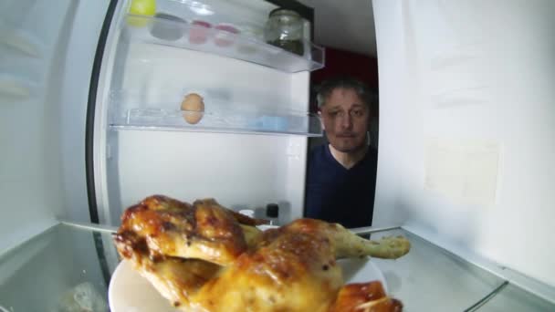 Небритый мужчина с похмельем ищет в холодильнике выпивку и что-нибудь поесть.. — стоковое видео