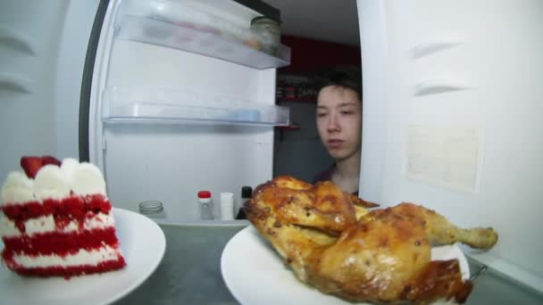 Un adolescente busca comida en el refrigerador. — Vídeo de stock