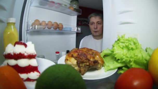 男は食べ物の冷蔵庫を見ている。燻製鶏や野菜と果物を選択するには — ストック動画