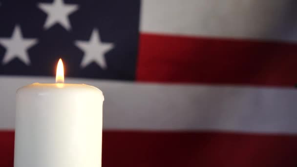 Ett ljus på bakgrunden av den amerikanska flaggan. En dag av minne, firande och sorg. — Stockvideo