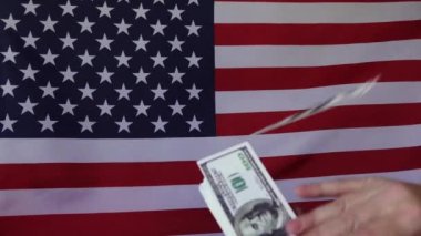 Amerikan bayrağının arka planına dolar düşmesi. Ağır çekimde. Para yağmuru.