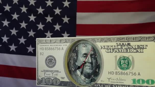 Biljet van 100 dollar in de vorm van een horloge, op de achtergrond van de vlag van de Verenigde Staten van Amerika. — Stockvideo