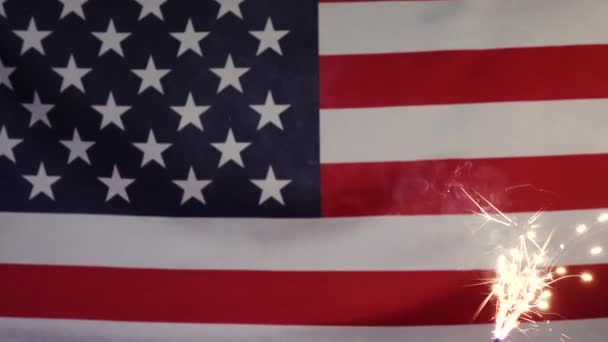 A sparkler candle on the background of the American flag. — Stock Video