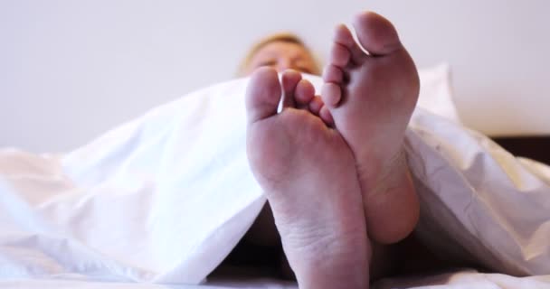 Женские ноги торчат из-под одеяла.. — стоковое видео