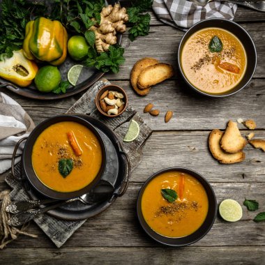 Kabak kremalı çorba fırında biber, havuç ve peynir, limon suyu ve zencefil, fındık ve taze nane ile servis edilir ahşap arka planda, üst görünüm ve köy tarzı.