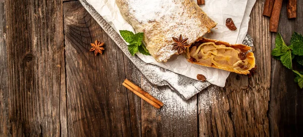 Postre austriaco crujiente al horno: strudel de manzana de masa de phyllo con manzanas caramelizadas, canela, pasas servidas en una tabla de madera con anís estrellado, palitos de canela, vista superior, espacio de copia — Foto de Stock