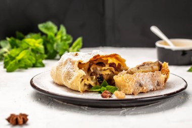 Baharatlı armutlu strudel, tarçınlı armutlu tatlı strudel, kuru üzüm, pudra şekeri ve nane. Avusturyalı Alman yemekleri.