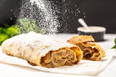Strudel with pears with raisins and mint sieve sprinkling sugar powder from above. on light background. copy space clipart
