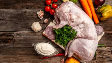 Tavşan eti. Genç ve taze bir tavşanın tüm leşi. Sebze ve baharatlı ahşap bir masada tavşan. Metin için boşluk. en üstteki görünüm.