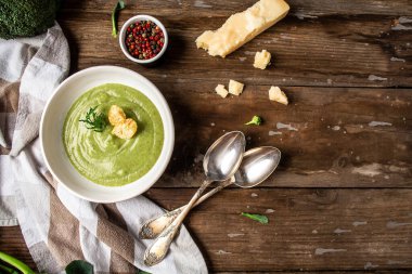 Beyaz kasede parmesanlı ev yapımı brokoli kremalı çorba, ahşap arka planda kızarmış ekmek. Temiz yemek, diyet, vejetaryen, vejetaryen, sağlıklı gıda konsepti, Top view.