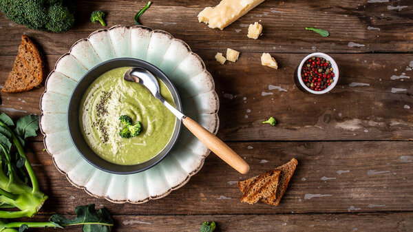 Fresh broccoli soup on bowl on wooden background. Long banner format. Vegetarian and diet food.