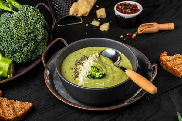 Green vegetable broccoli soup puree on a dark wood background. banner, catering menu recipe, top view.