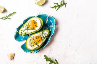 Avokadoda yumurta ve taze otlar ve baharatlar. Yumurtayla doldurulmuş avokado. Nefis bir kahvaltı ya da hafif bir arka planda atıştırmalık..