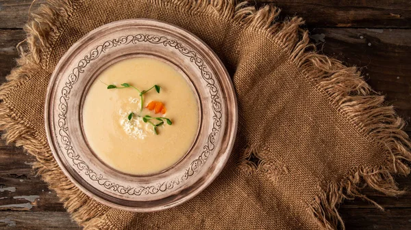 Chicken and coconut milk soup on rustic wooden table with burlap napkin, Long banner format, top view, copy space.