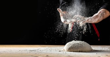 Güzel ve güçlü erkeklerin elleri hamuru yoğurarak ekmek, makarna ya da pizza yaparlar. Bir un bulutu toz gibi uçuşuyor. Yiyecek konsepti