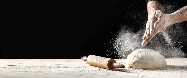 Beyaz takım elbiseli pasta şefi beyaz toz kaplı masaya top hamuru fırlatırken beyaz un havaya uçuyor. Doğa, İtalya, gıda, diyet ve biyoloji kavramı.