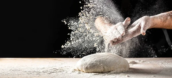 Photo of flour and men hands with flour splash. Cooking bread. Kneading the Dough. Isolated on dark background. Empty space for text.