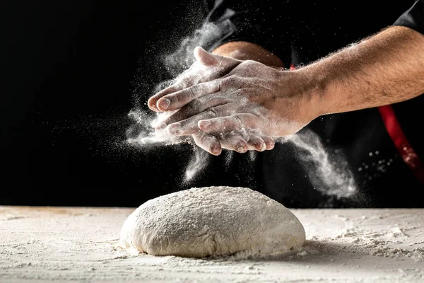 Profesyonel şefin el çırpışı ve yemek pişirme kabı ile koyu arkaplanlı un sıçraması. Karanlık arka planda izole edilmiş. Metin için boş boşluk.