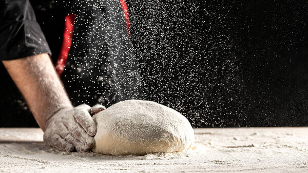 Photo of flour and men hands with flour splash. Cooking bread. Kneading the Dough. yeast dough for bread or pizza on a floured surface.