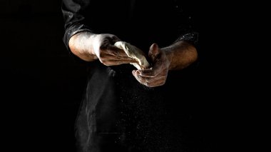 Pizza için taze hamura un serpiştiren, ekmek pişiren bir adam. Hamuru yoğurmak, un sıçratan erkekler..