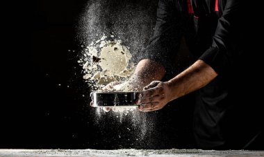 Tozlu un havaya karışıyor. Erkek eli un sıçraması. Ekmek pişiriyorum. Hamuru yoğurmak. Yemek tarifi geçmişi. Metin için boşluk.